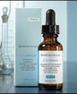 SkinCeuticals C E Ferulic skincare serum and packaging on a reflective surface.